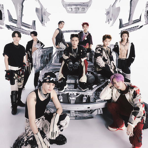 Album concept picture for NCT 127's "2 Baddies", which features them centered around a deconstructed Porsche with a white backdrop. From left to right: Jungwoo, Johnny, Taeyong, Doyoung, Jaehyun, Mark, Taeil, Haechan, Yuta.